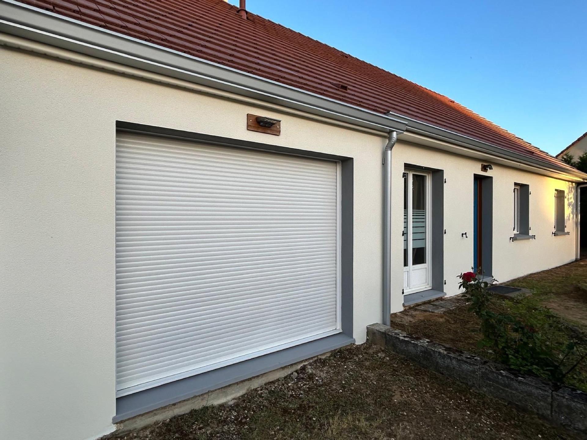 Façade de maison en crépi beige avec volet roulant et porte d'entrée, ravalement réalisé par la Société Peinture Malas près d'Alençon