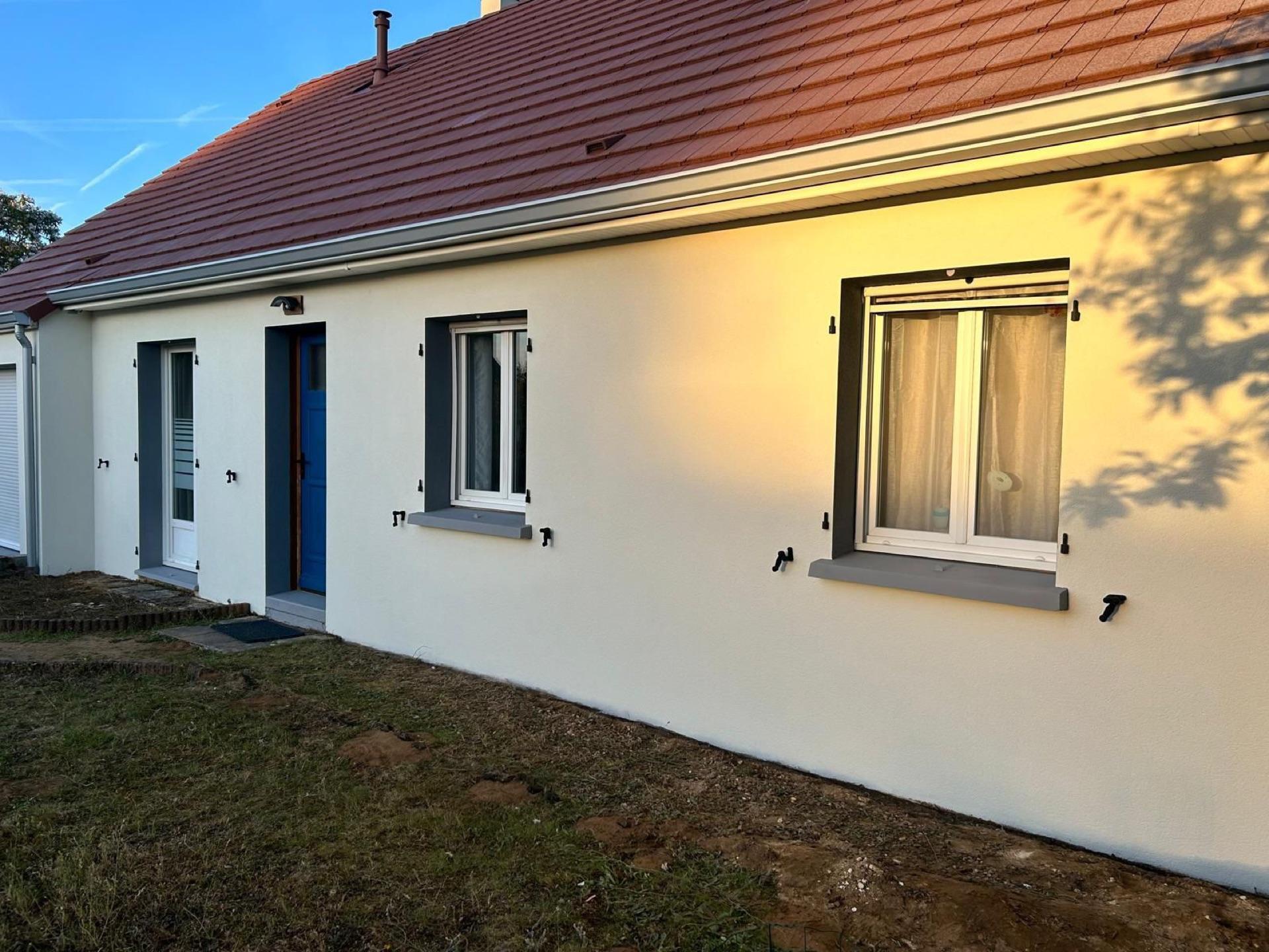 Façade rénovée en crépi beige clair avec volets gris au soleil couchant, réalisée par la Société Peinture Malas