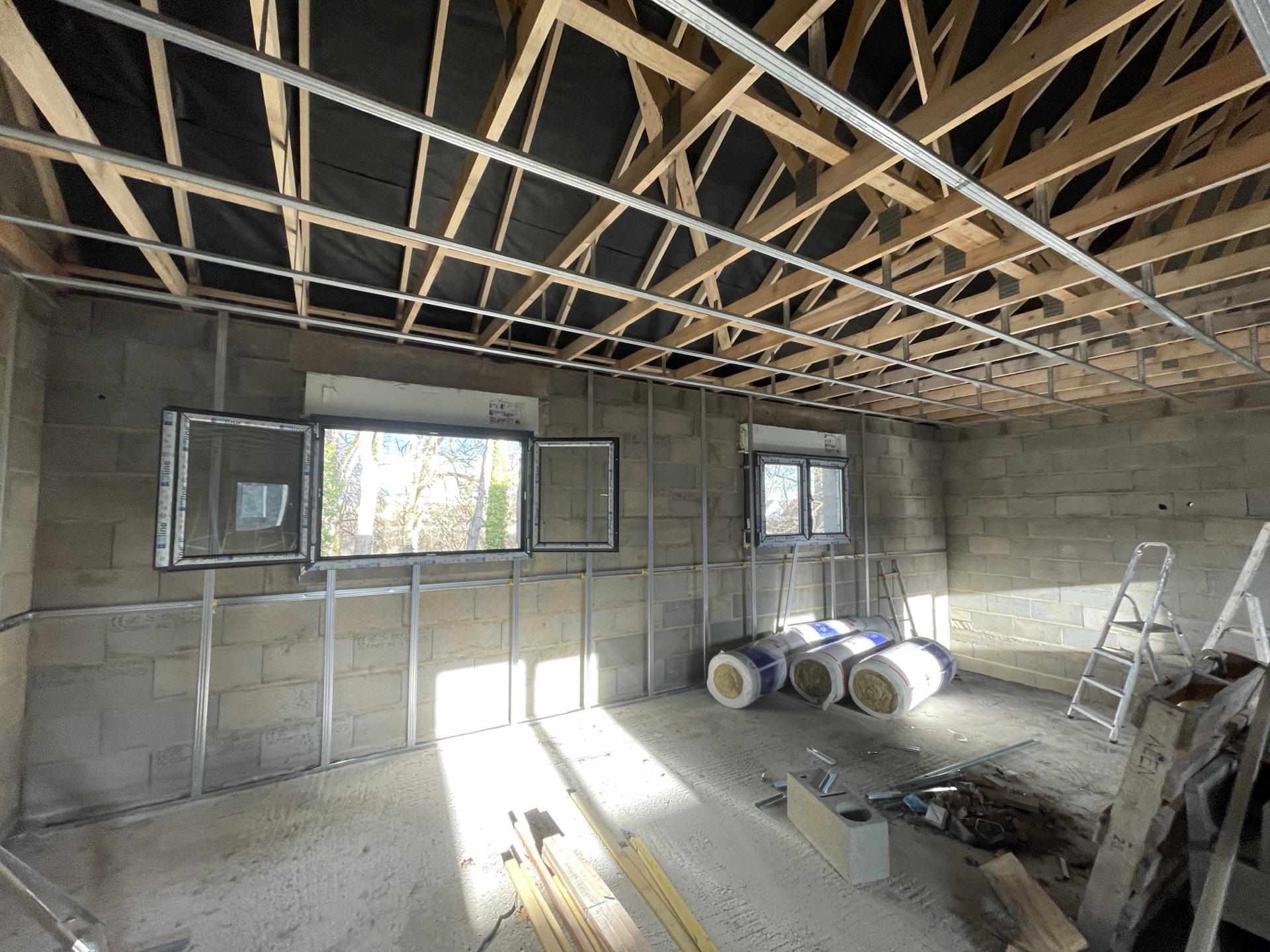 Ossature métallique de plafond et charpente apparente lors d'un chantier d'isolation et de placo