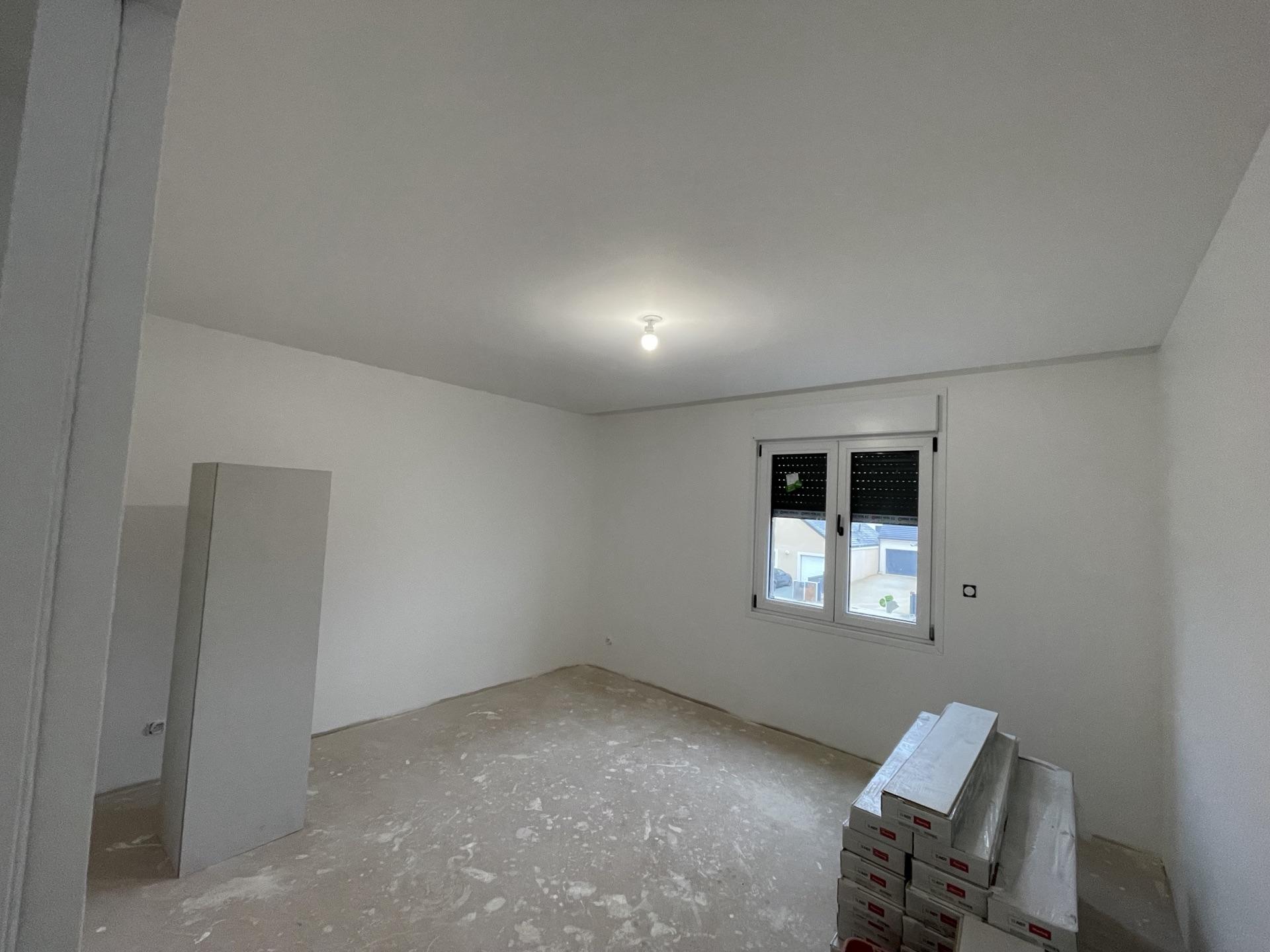 Pièce de vie repeinte en blanc avec fenêtre, murs et plafond uniformes